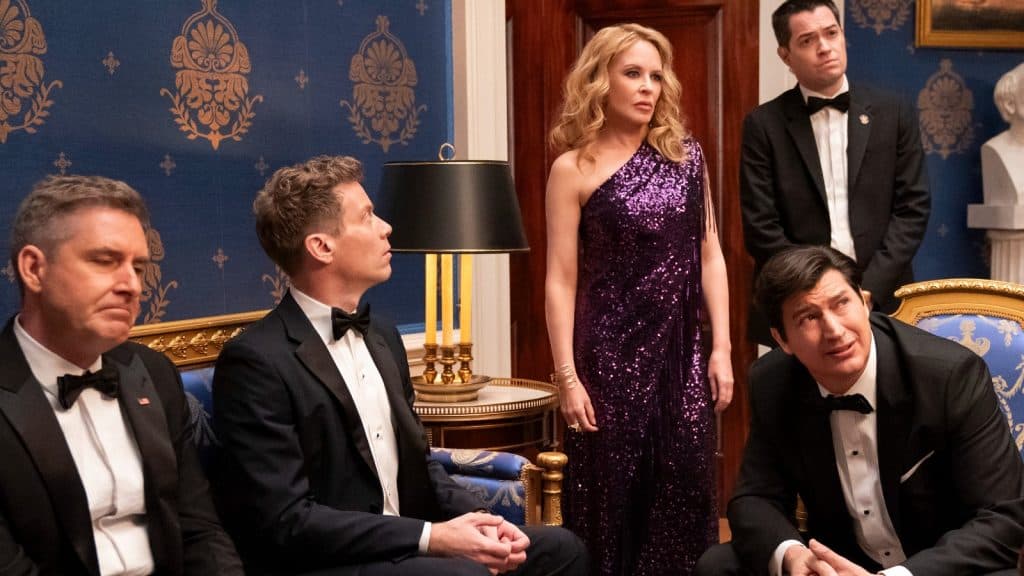 Kylie Minogue ladeado por homens na residência.